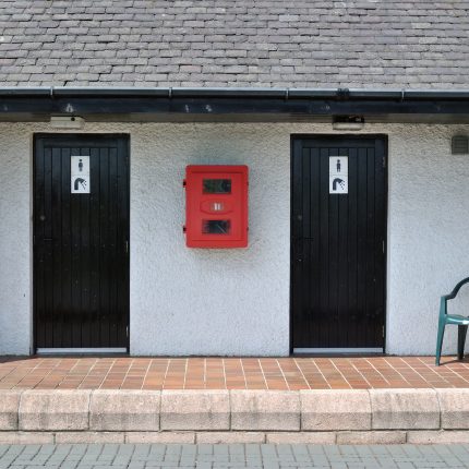 Public,Toilet,Building,With,Black,Painted,Wooden,Doors,&,Green